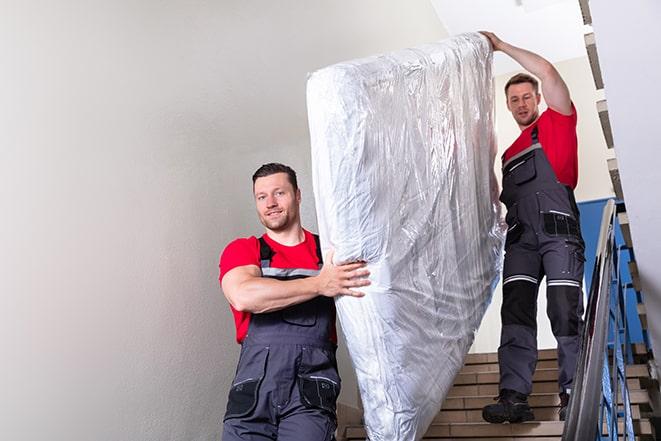 two people carrying a box spring out of a room in Bordentown